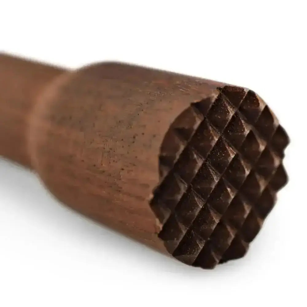 Wooden cocktail muddle with textured surface on a white background