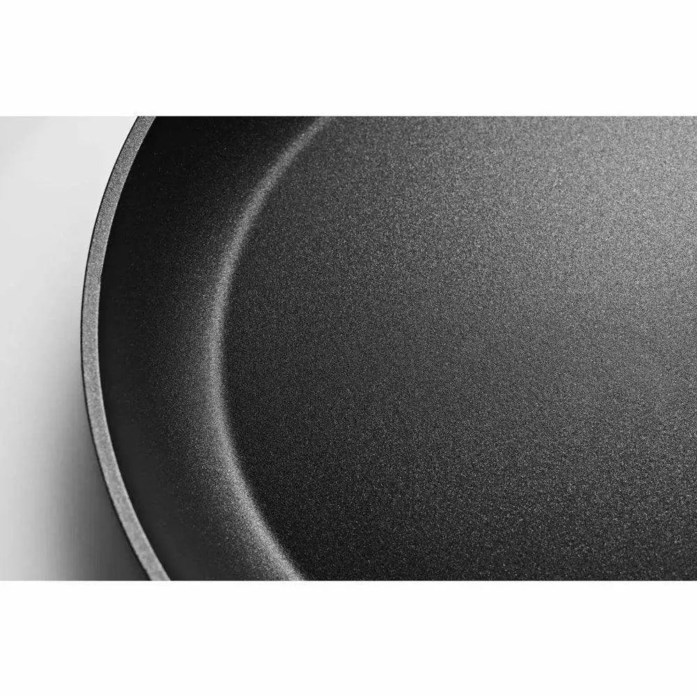 Close-up of a black frying pan with a textured surface on a white background