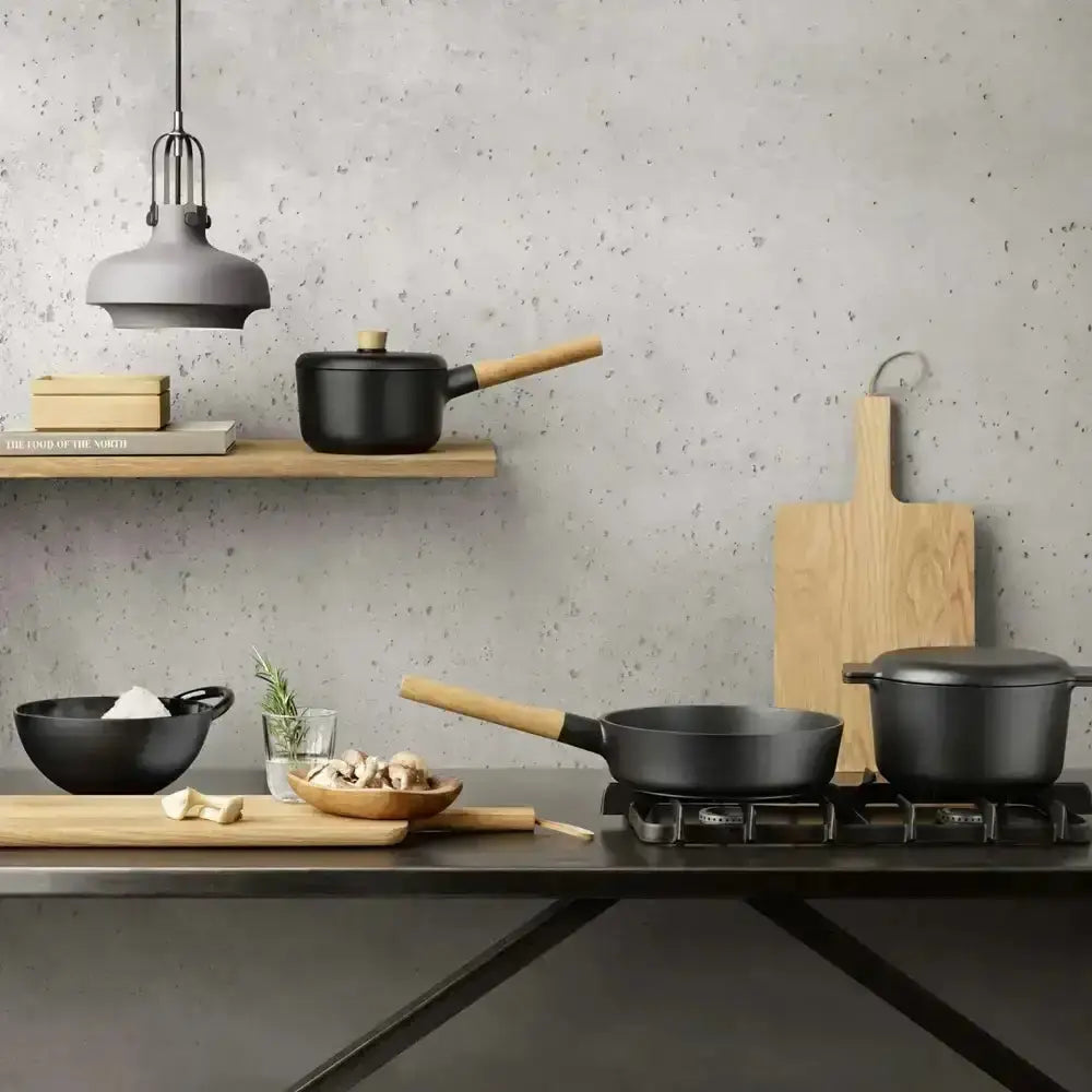 Modern kitchen with black cookware on a gray countertop and speckled gray wall.
