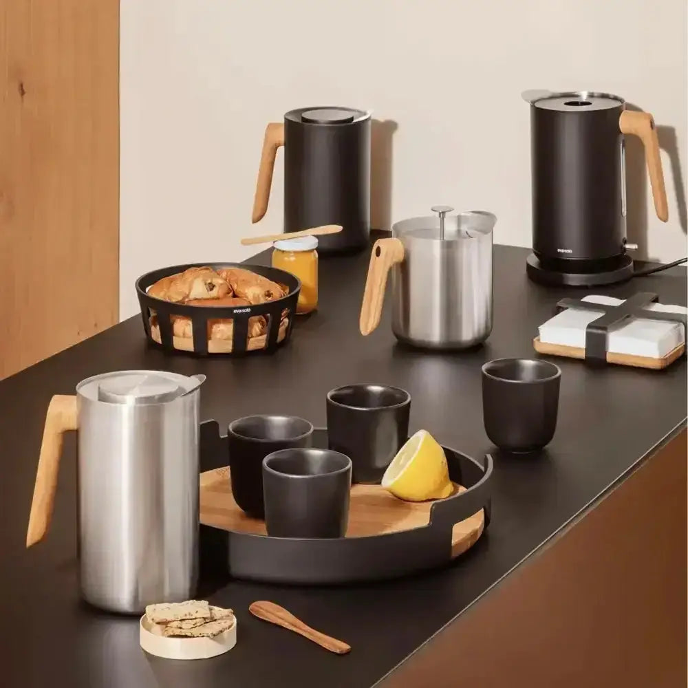 Kitchen counter with coffee-making equipment and snacks on a wooden surface.