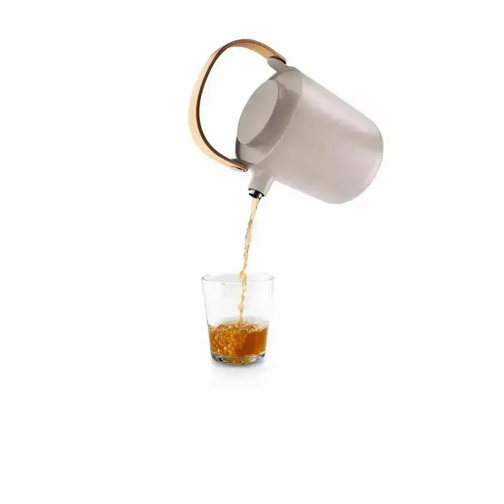 Eva Solo Nordic tea vacuum jug in sand color pouring tea into a glass, Cookin Stores kitchenware.