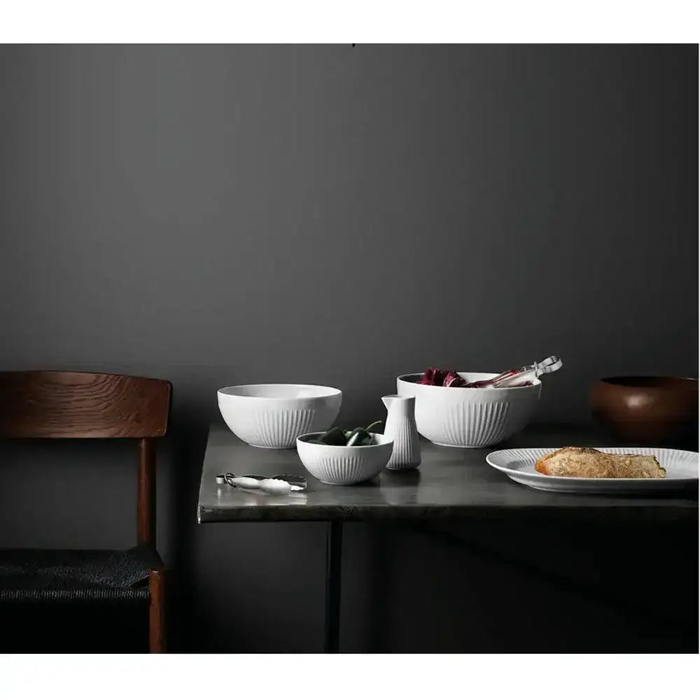 Dining setup with bowls, plates, and a chair against a dark gray wall.