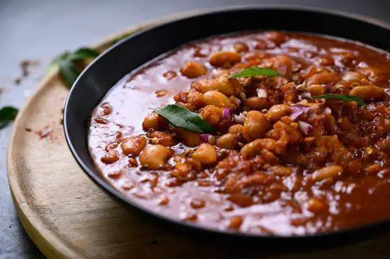 Hearty bean stew served in a black bowl on wooden board, premium kitchenware at Cookin Stores