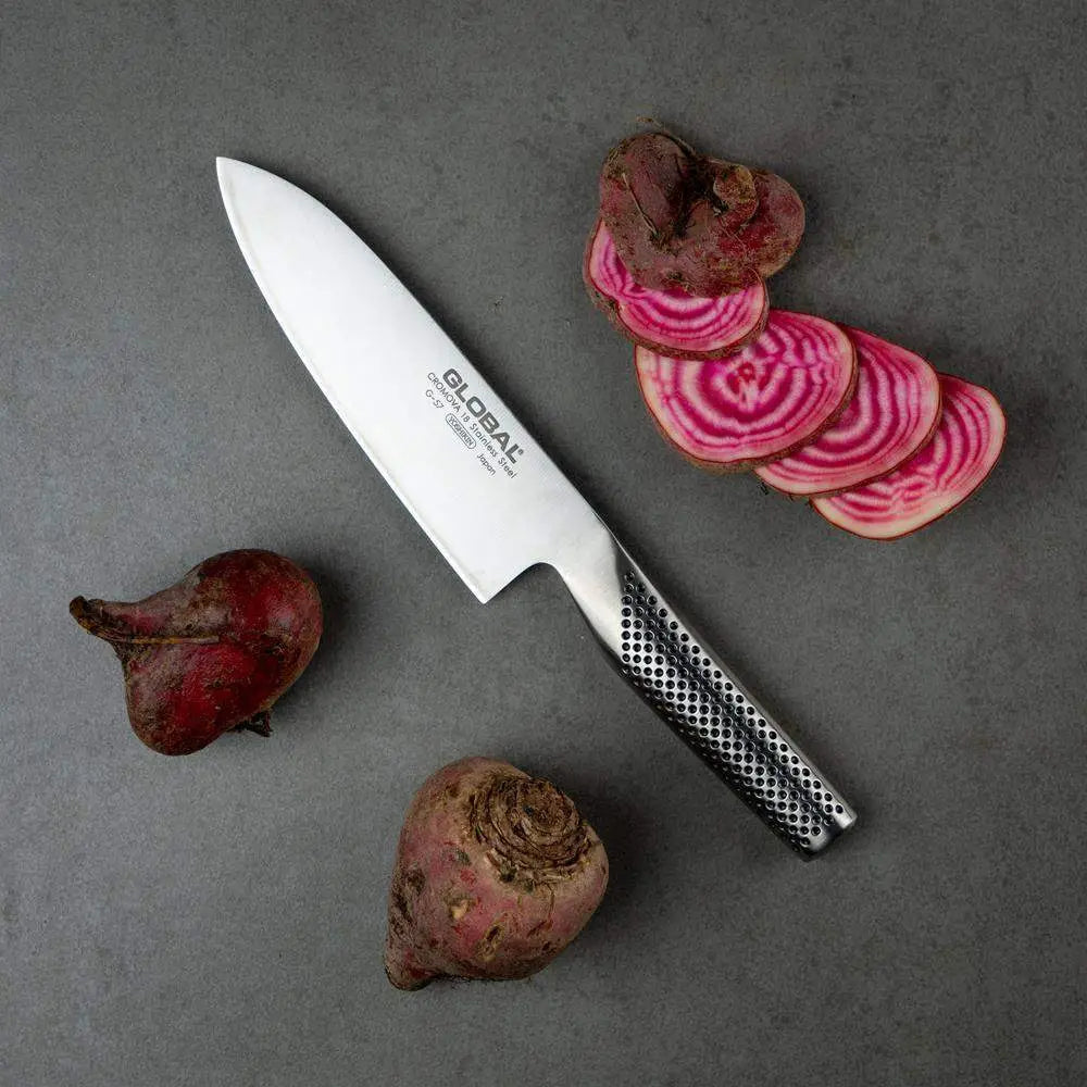 Chef's knife with sliced beets on a gray surface