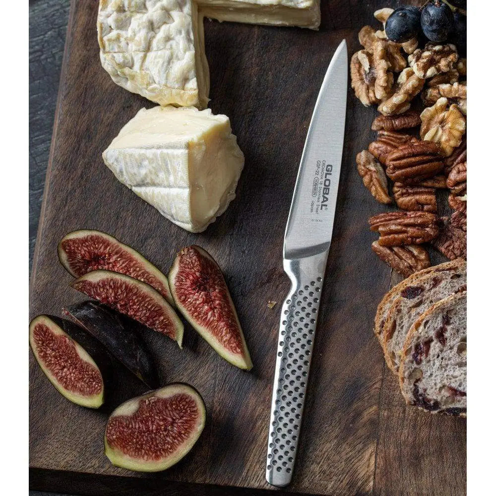 Knife on a wooden board with cheese, figs, nuts, and bread