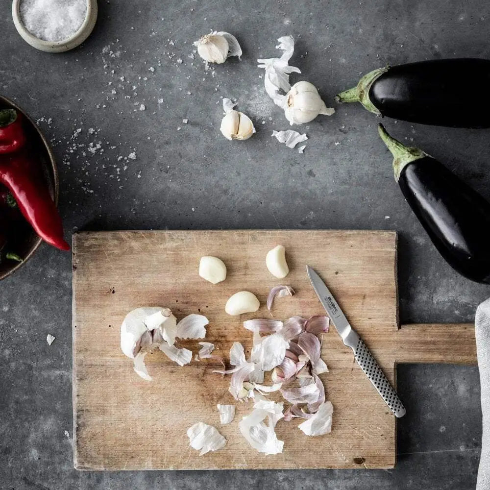 Wooden cutting board with chopped ingredients and a knife on a dark surface