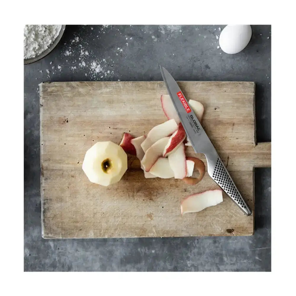 Wooden cutting board with sliced apples and a knife on a dark surface