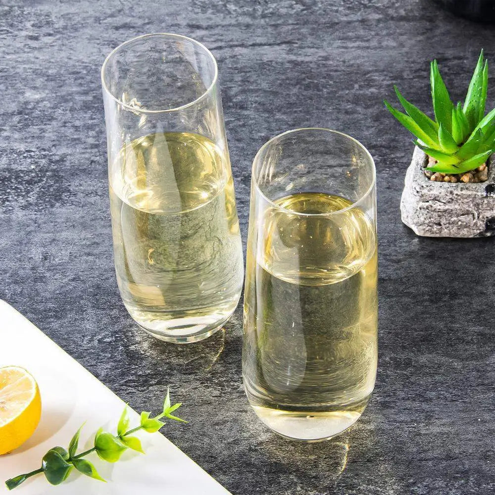Two glasses of white wine on a dark stone surface with a lemon and plant in the background.