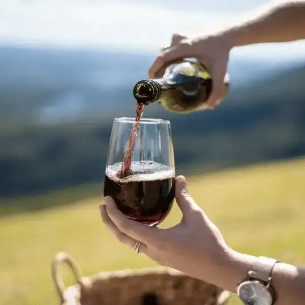 Pouring red wine into Govino outdoor wine glass, picnic basket in background, Cookin Stores