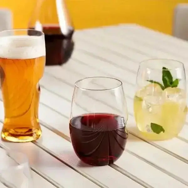 Three glasses of different drinks on a wooden table with a yellow wall in the background.