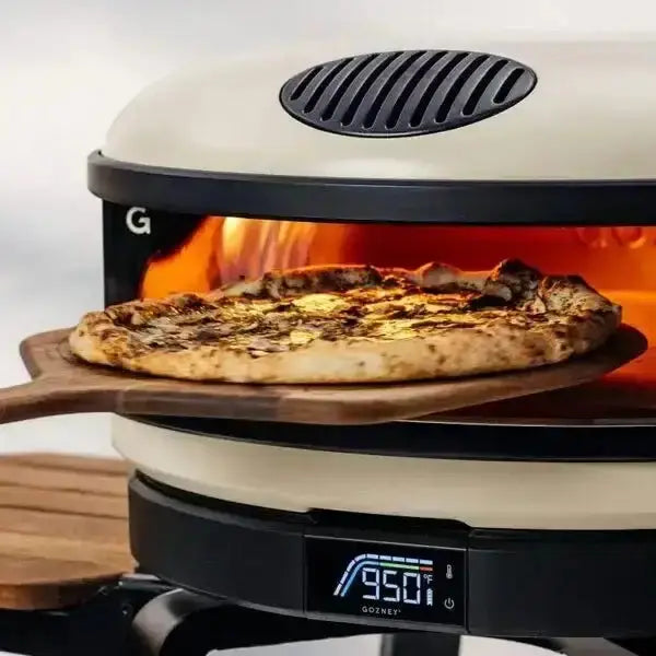 Gozney acacia wood pizza peel with fresh pizza in a hot pizza oven at Cookin Stores