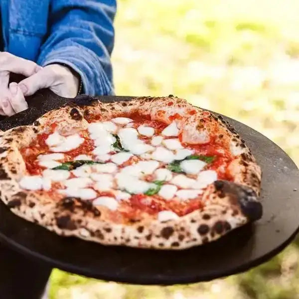 Wood-fired pizza on Gozney Black Fibre Pizza Server outdoors at Cookin Stores