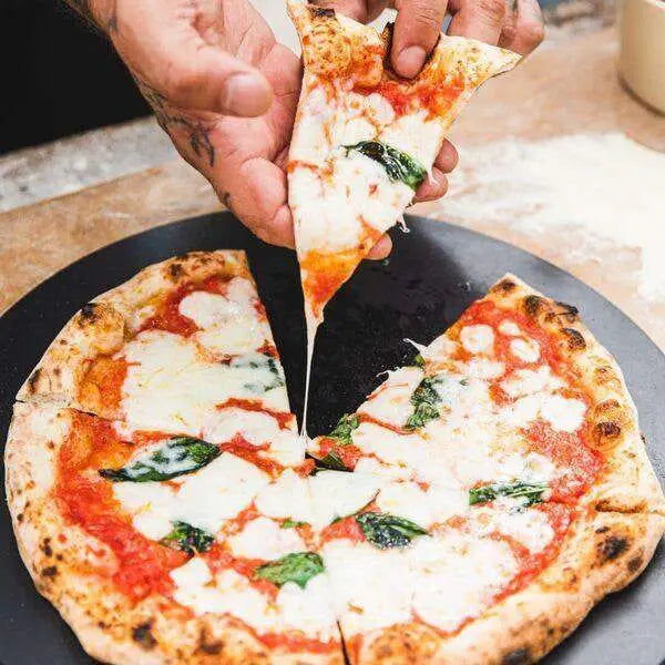 Hand serving Margherita pizza slice on Gozney black fibre pizza server, Cookin Stores kitchenware