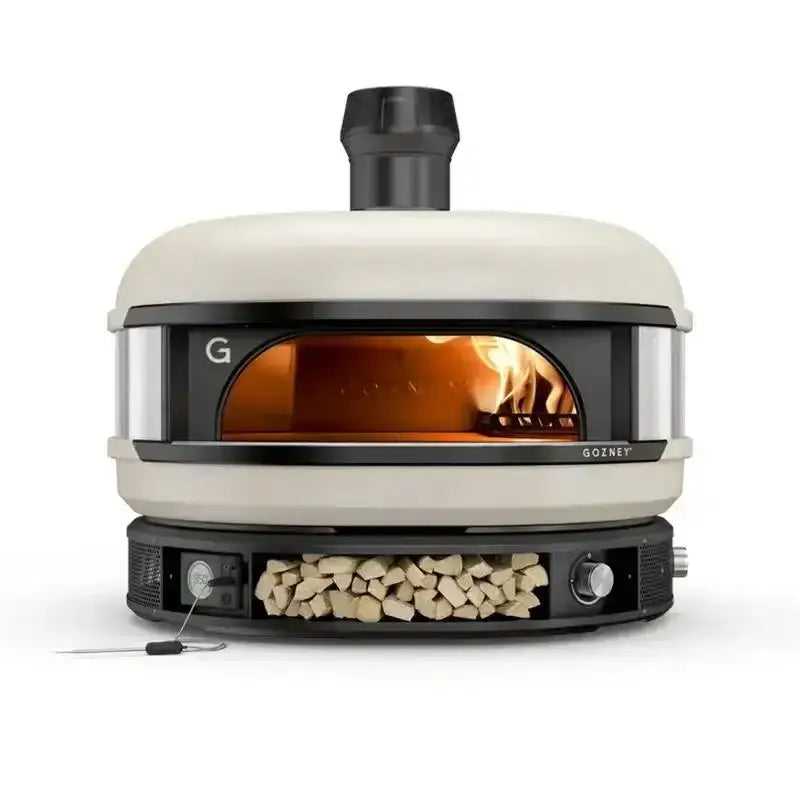 Gozney Dome Bone Dual Fuel Pizza Oven with fire burning, wood storage, premium kitchenware at Cookin Stores