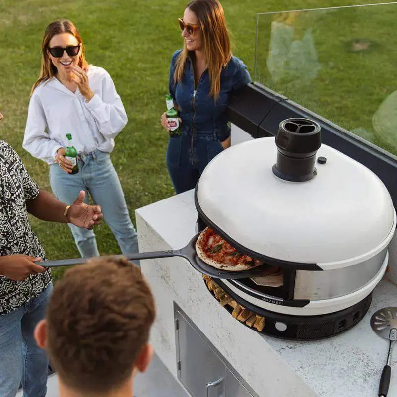 Friends enjoying outdoor pizza party with Gozney Dome Bone dual fuel pizza oven at Cookin Stores
