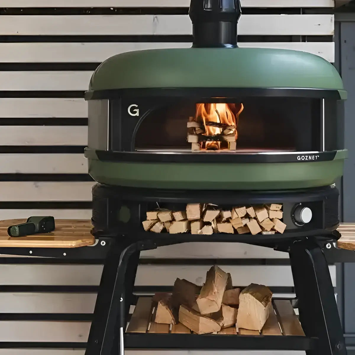 Gozney Dome multi-fuel outdoor pizza oven with wood fire, stacked logs, Cookin Stores kitchenware