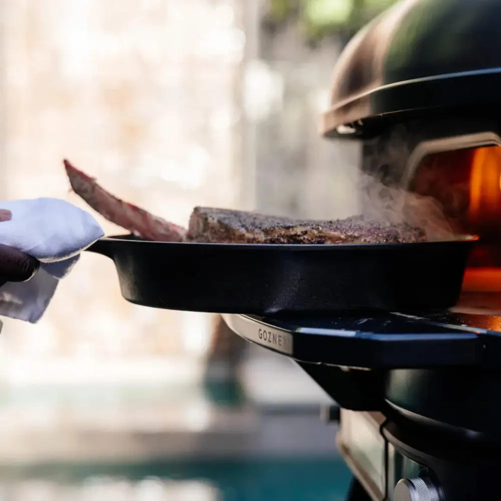 Person grilling on a portable grill with a scenic background