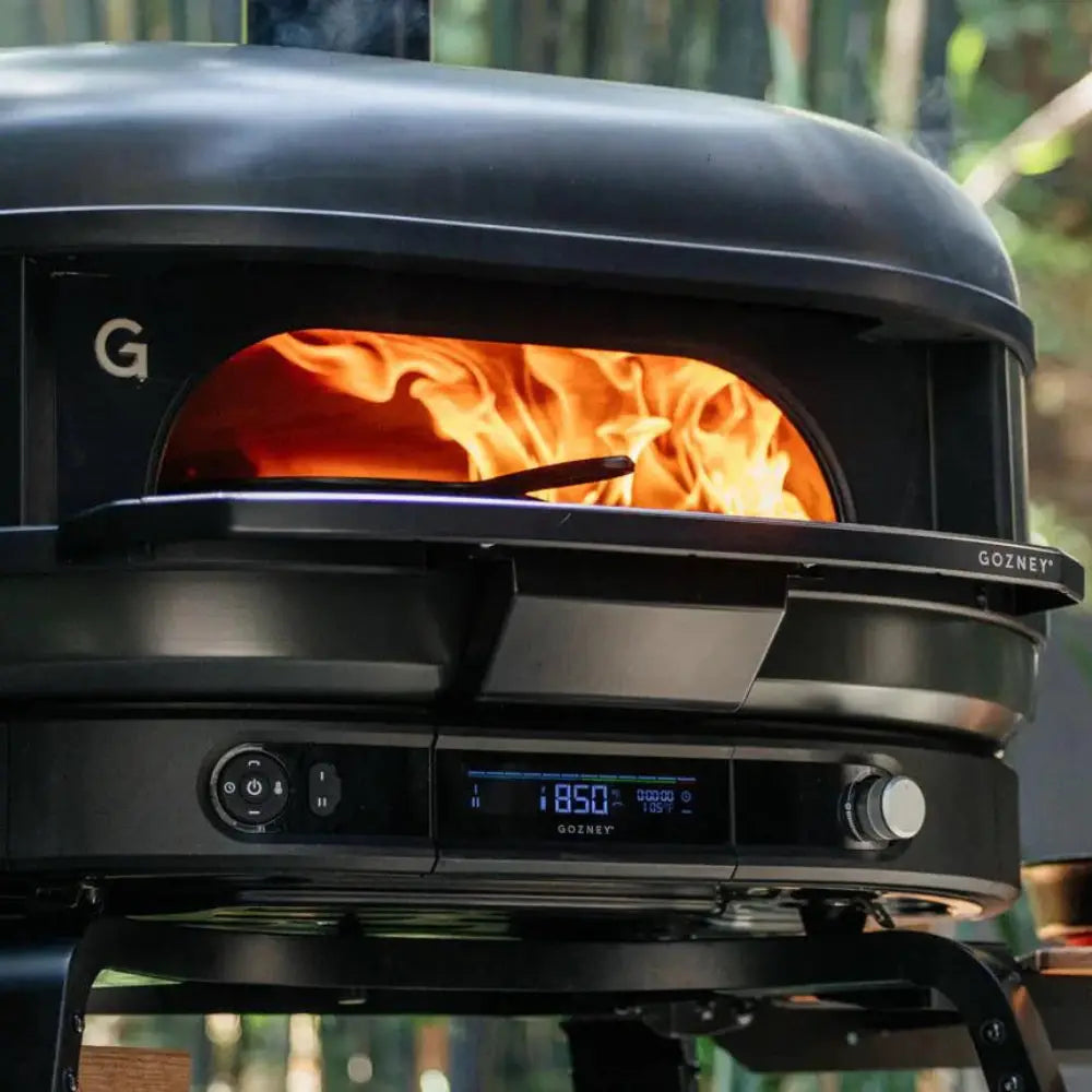 Black portable stove with visible flames on a wooden surface outdoors