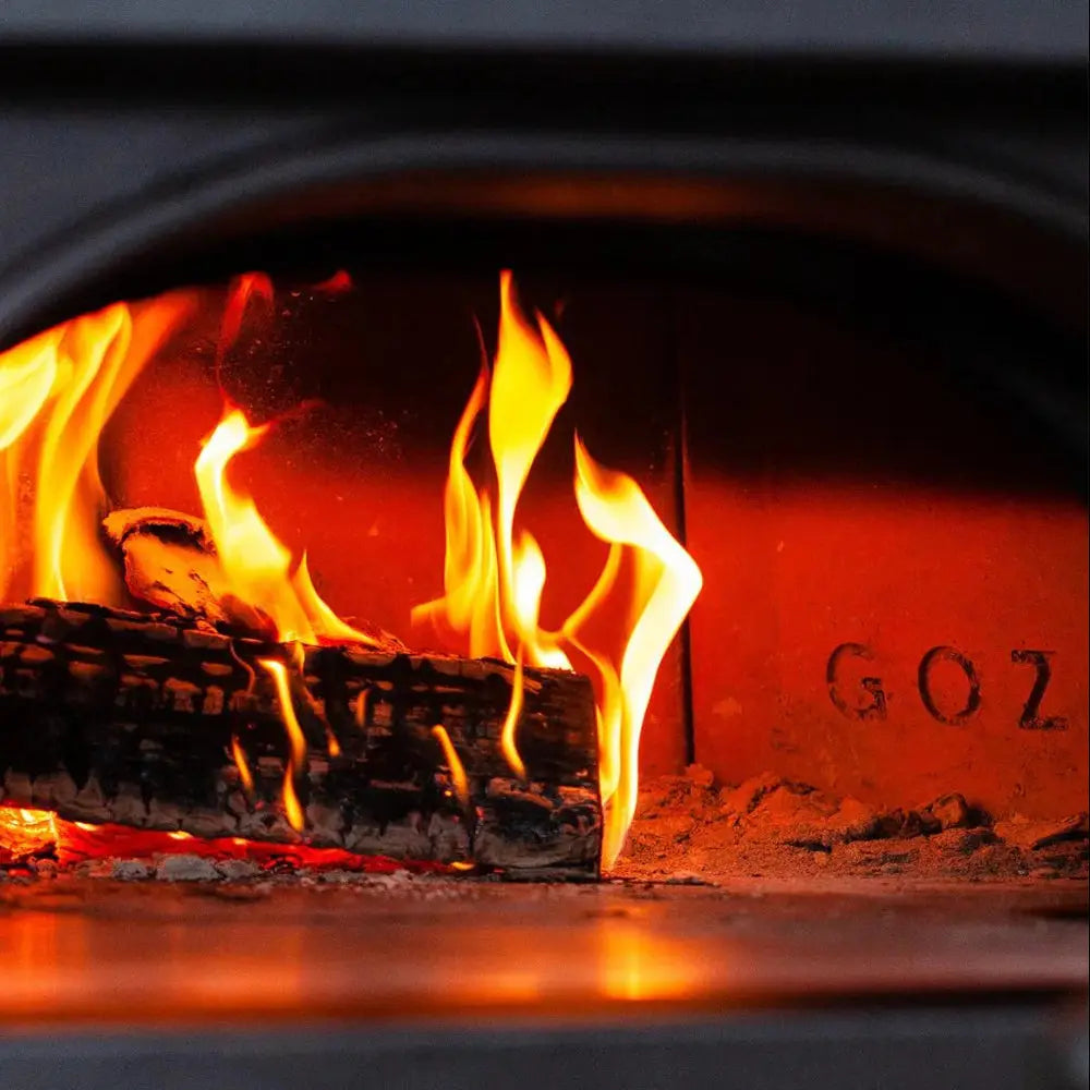 Wood burning in a fireplace with flames and glowing embers.