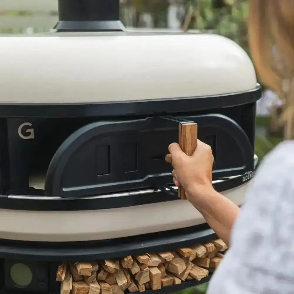 Hand opening Gozney Dome wood-fired oven door, outdoor pizza oven at Cookin Stores