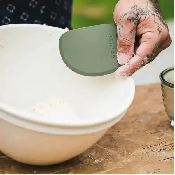 Hand using Gozney pizza dough scraper in mixing bowl on kitchen counter at Cookin Stores