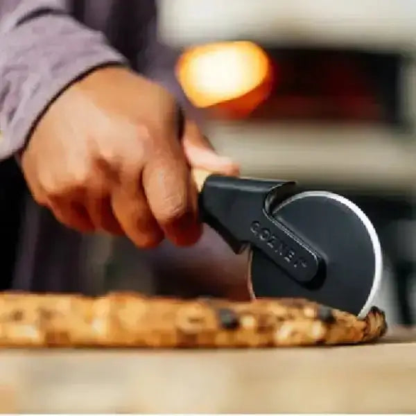 Person using a pizza cutter to slice a pizza on a wooden board.