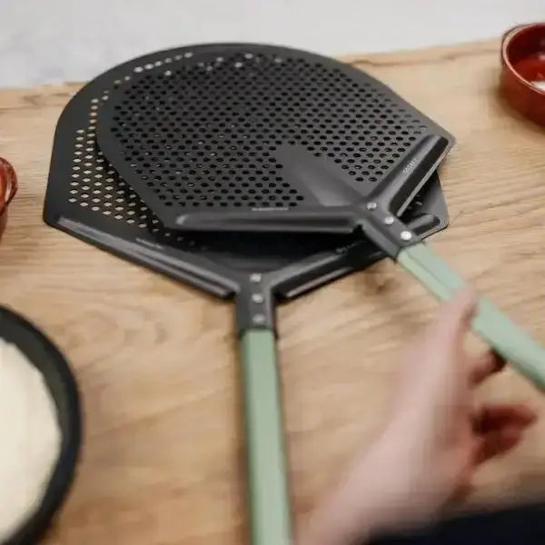 Gozney Pro pizza placement peel with green handle on wooden kitchen surface at Cookin Stores.