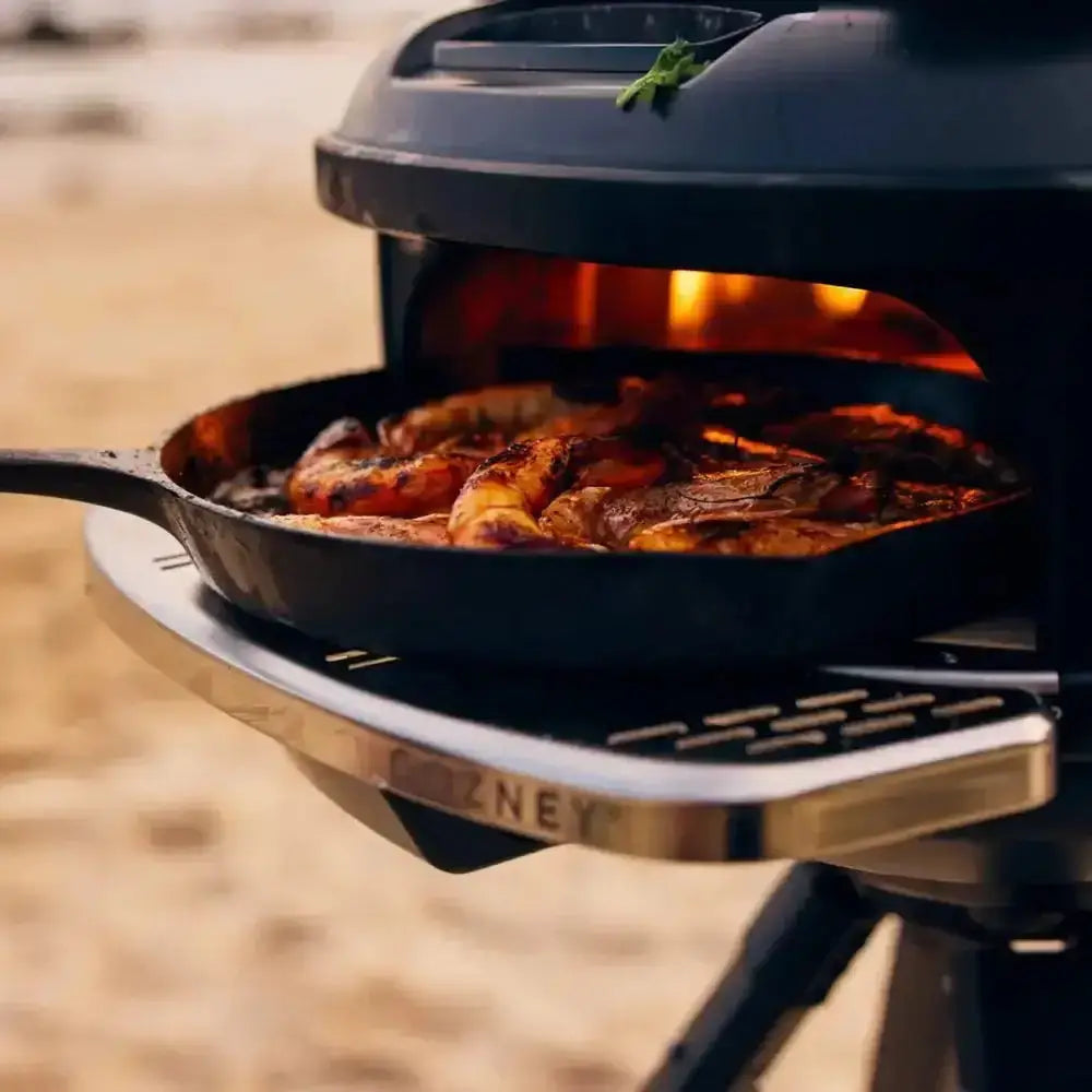 Gozney outdoor oven cooking shrimp and meat in cast iron pan, premium kitchenware at Cookin Stores
