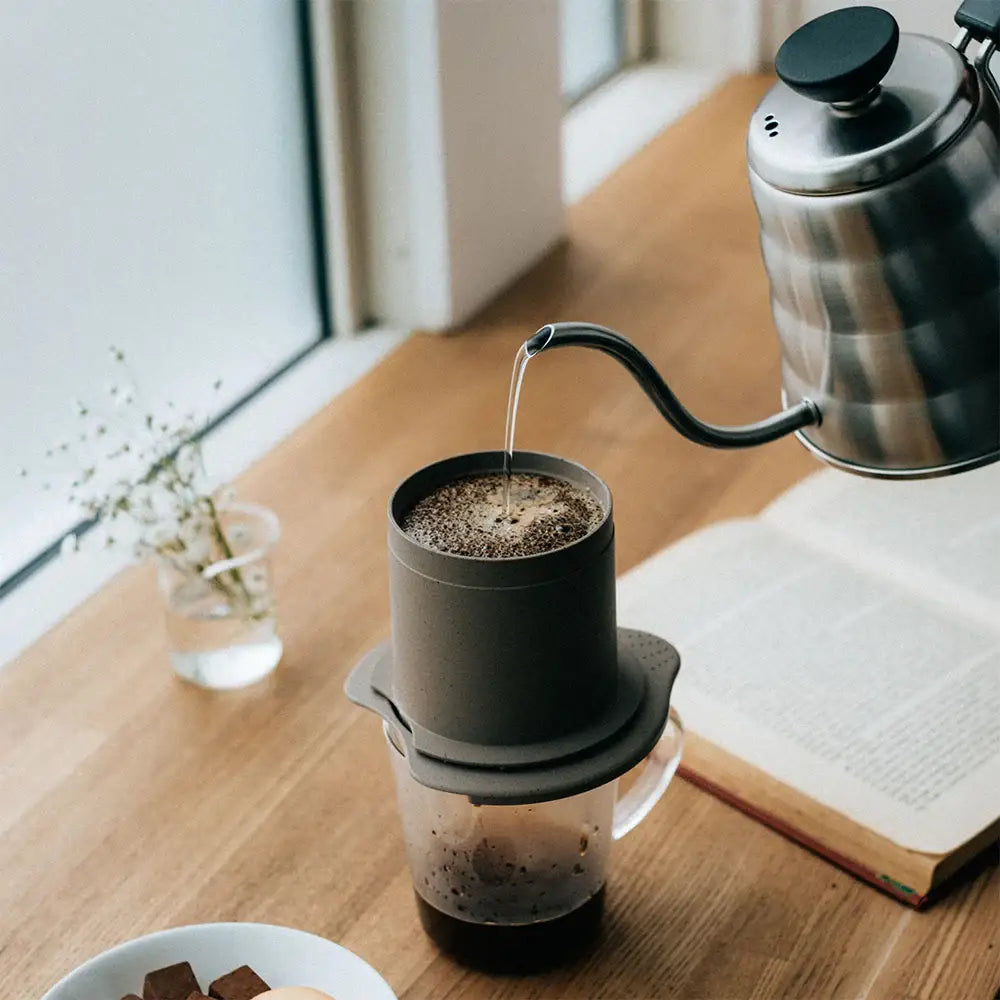 A sleek matte black hario baton cafeor paperless coffee dripper with clear glass base and lid for pour-over brewing
