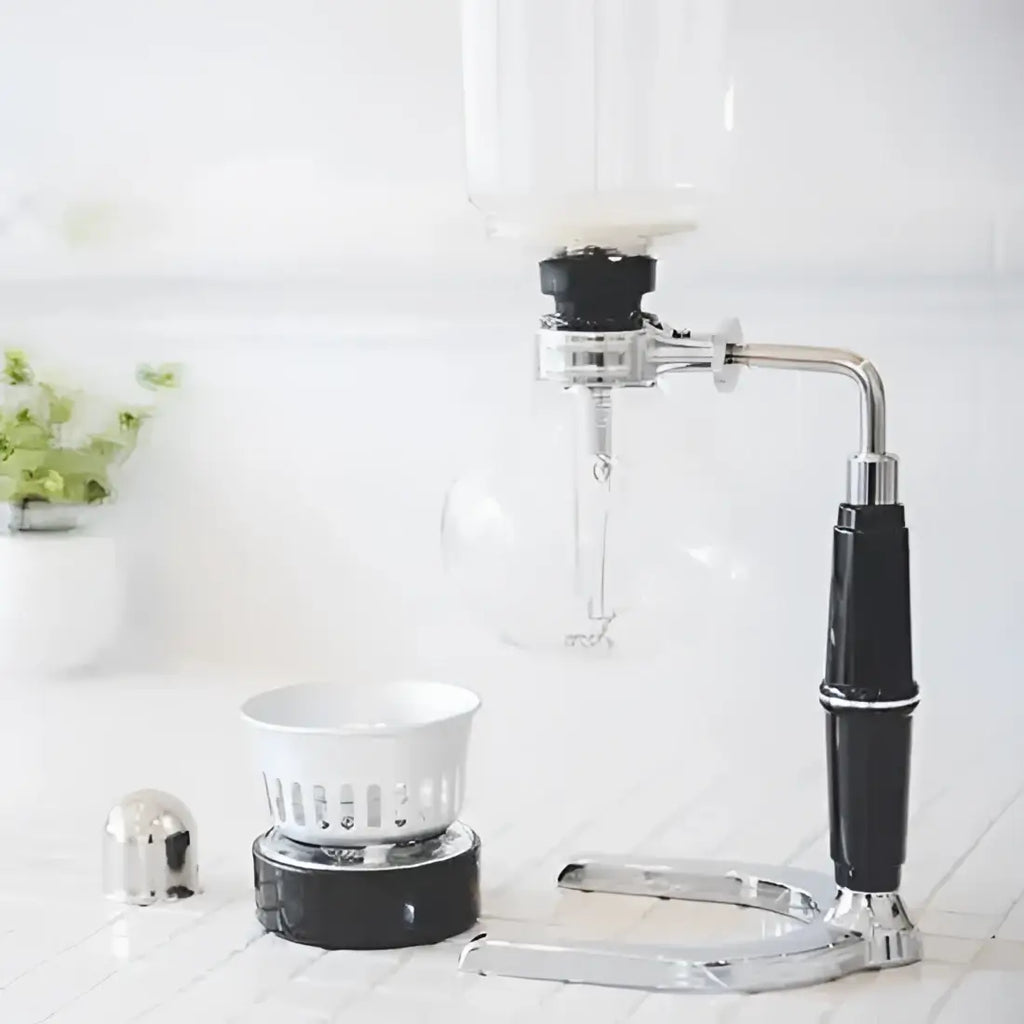 Manual coffee grinder with a white bowl on a light wooden surface.