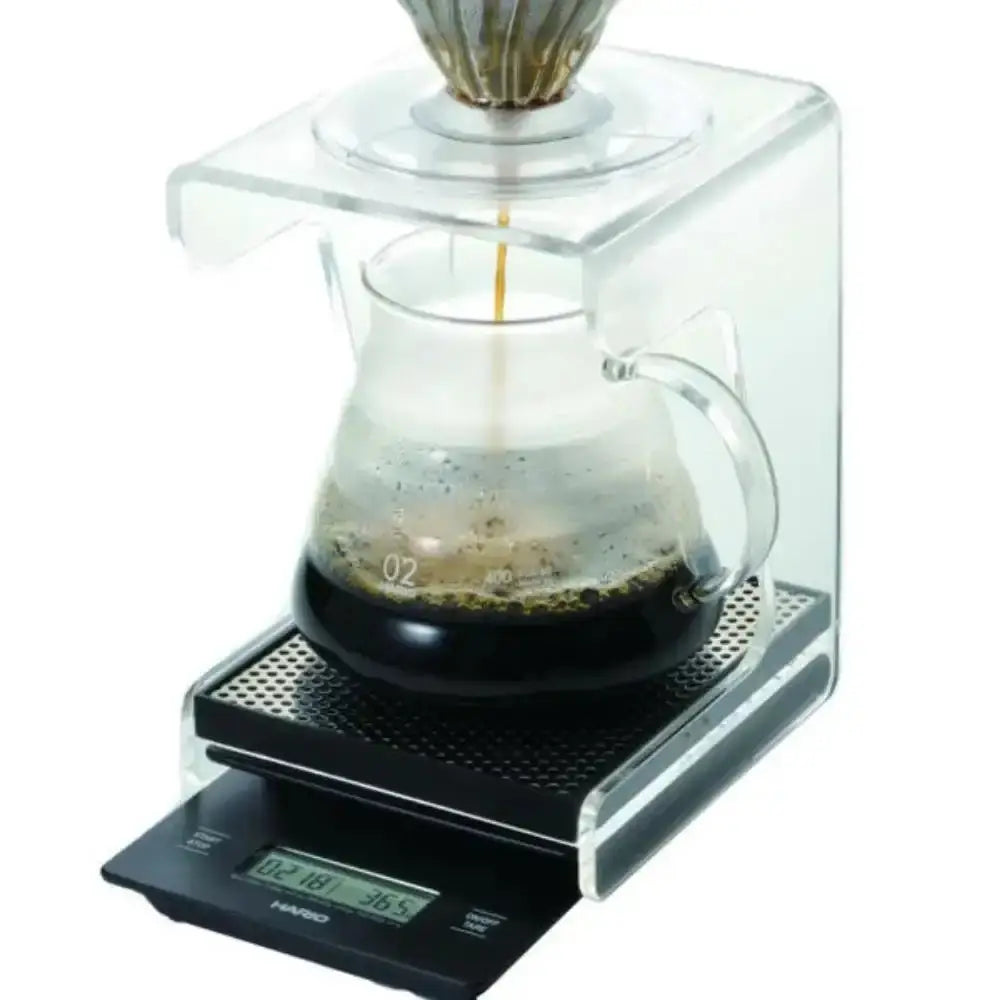 Coffee brewing process on a digital scale with a clear container and glass carafe.