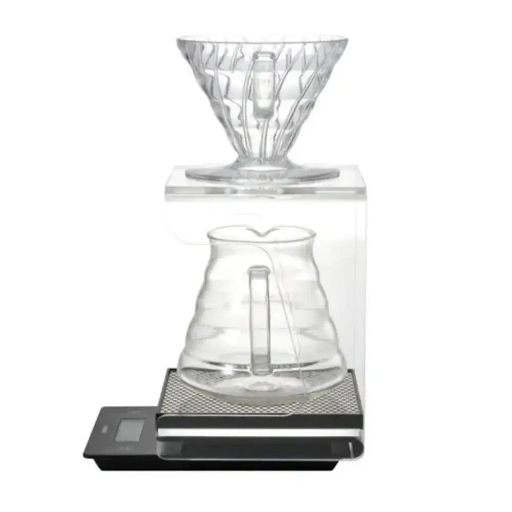Clear glass coffee brewing device on a digital scale with a white background