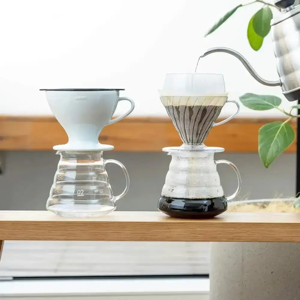Two coffee brewing devices on a wooden surface with a blurred background