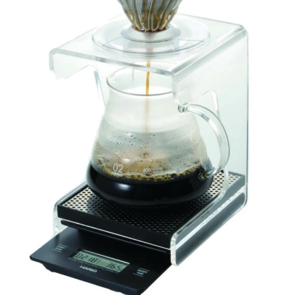 Coffee brewing process on a digital scale with a clear container and glass carafe.