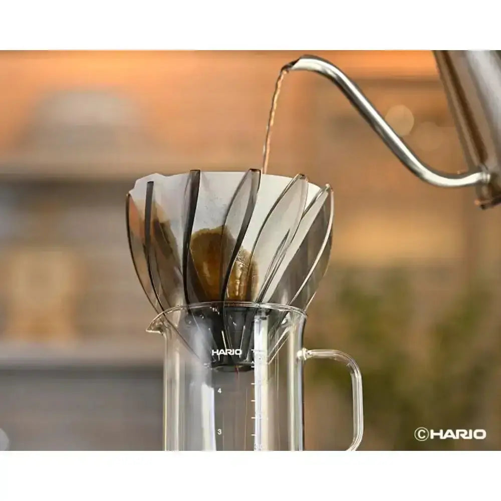 Coffee being poured into a Hario coffee filter with a blurred background