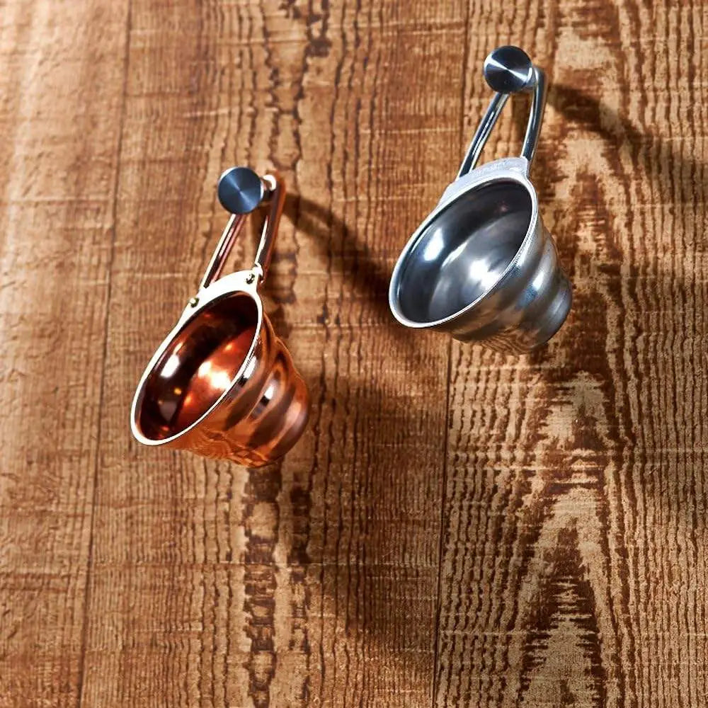 Two metal cups, one copper and one silver, on a wooden surface.