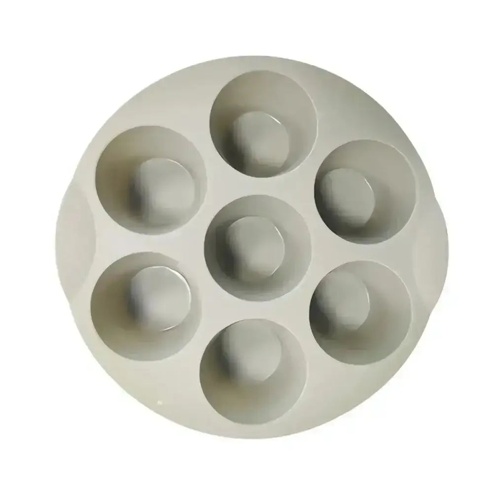Gray silicone mold with six circular cavities on a white background