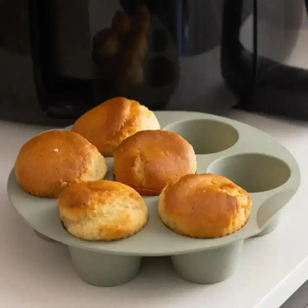 Muffins in a green muffin tray on a white surface