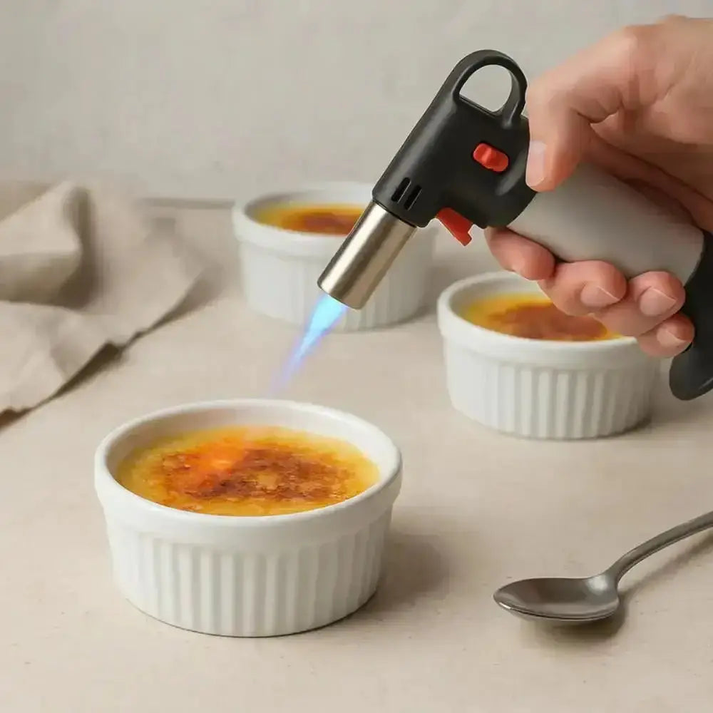 Hand using chef's blow torch to caramelize crème brûlée in white ramekin, premium kitchenware