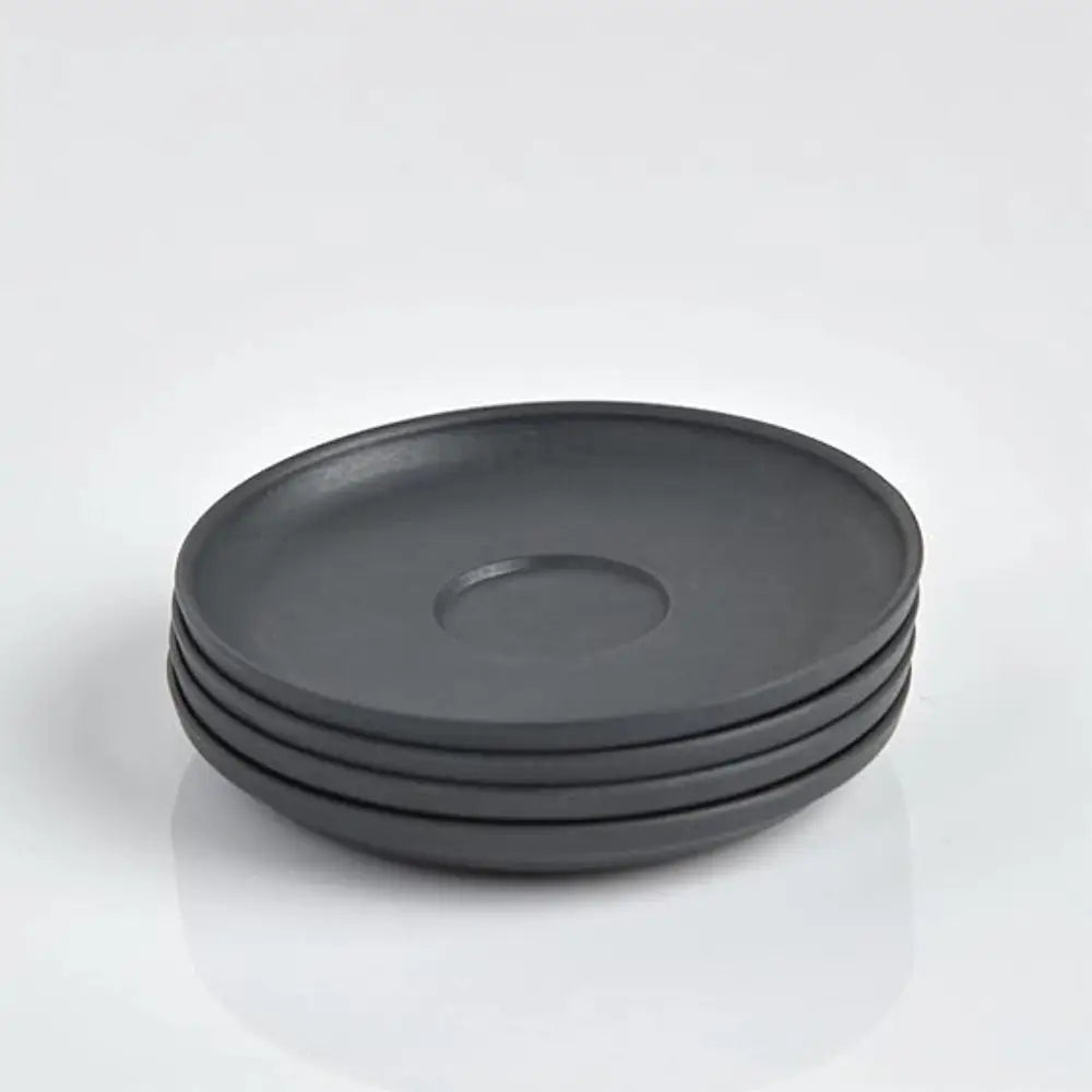 Stack of four dark gray saucers on a white background