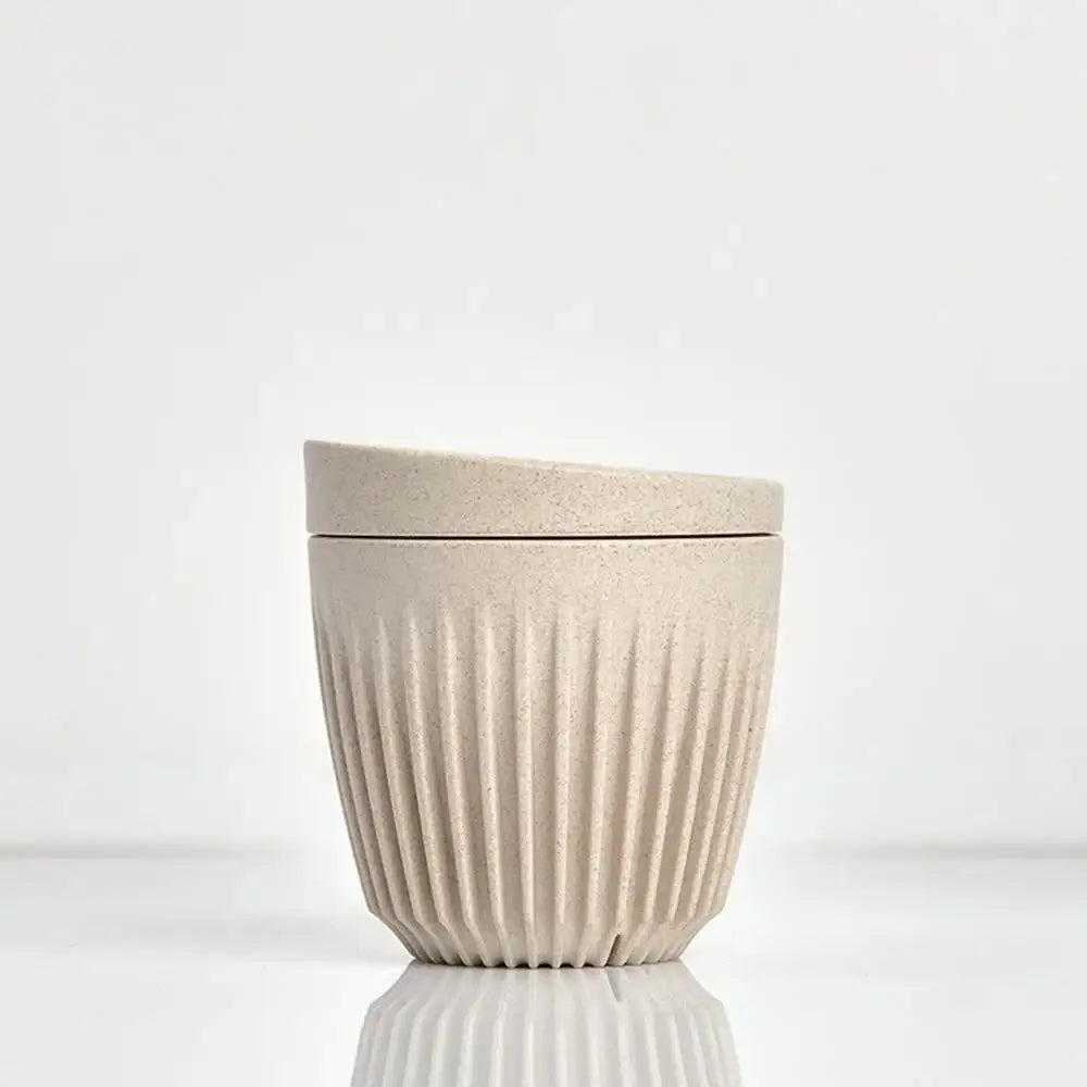 Beige ceramic cup with lid on a white background