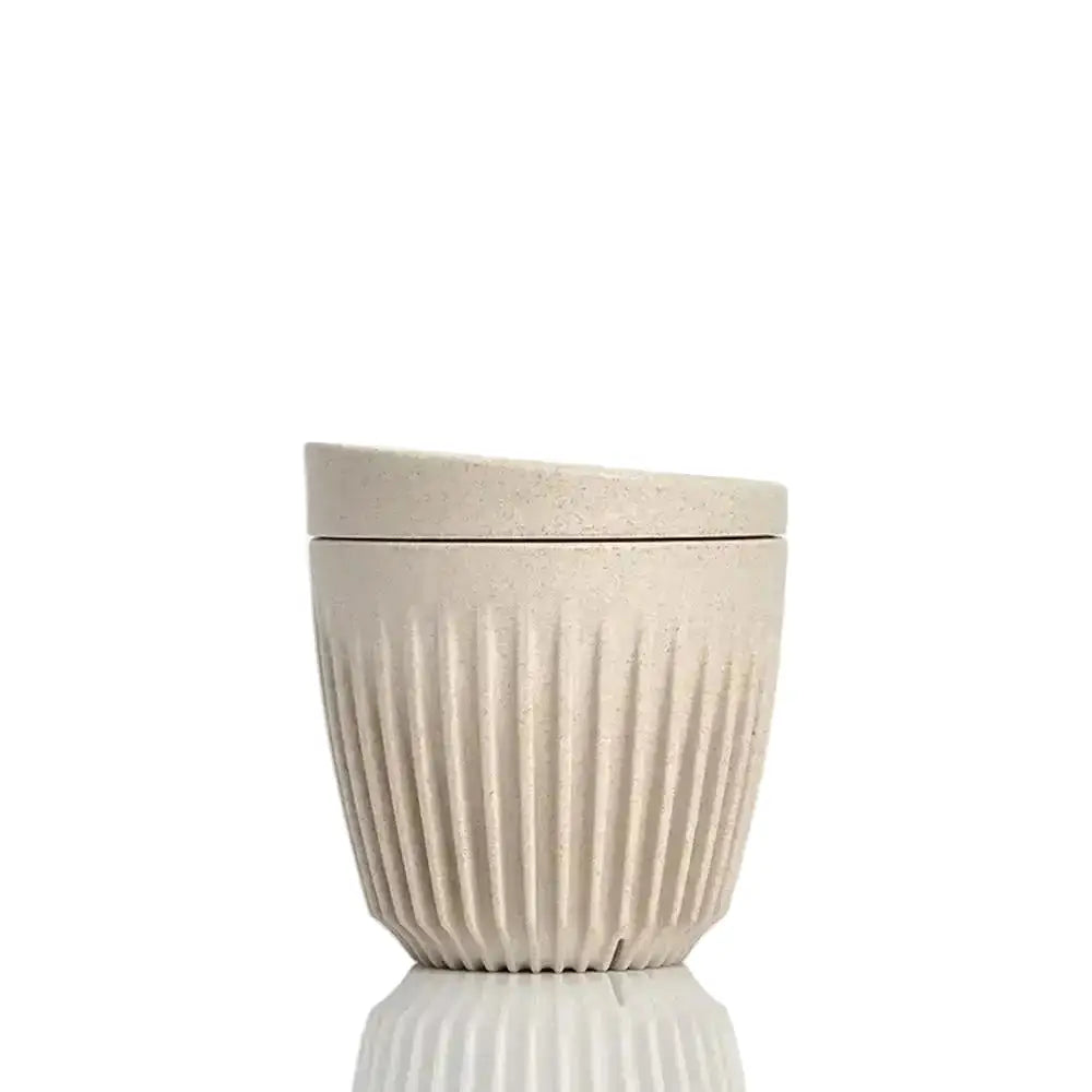 Beige ceramic cup with lid on a white background