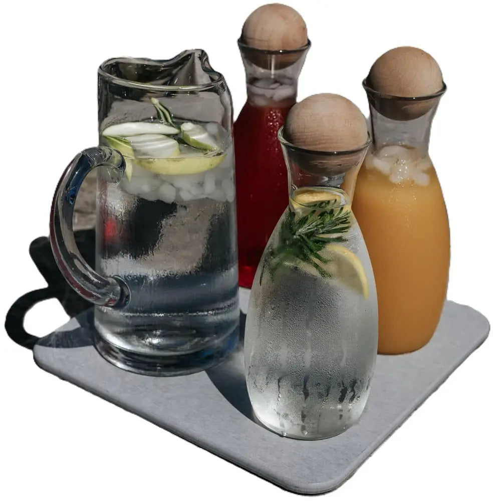 Set of glass pitchers with different drinks on a gray tray