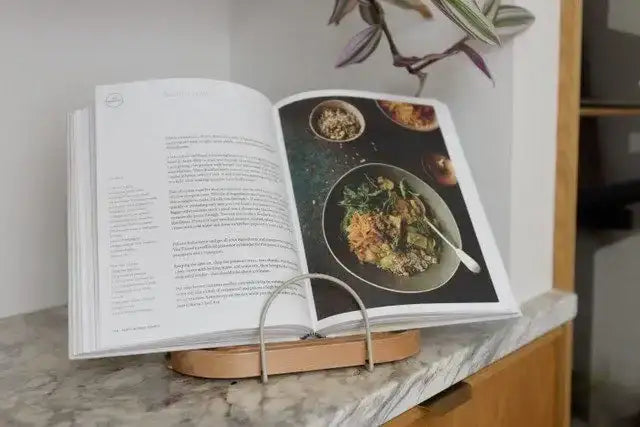 Open cookbook on a marble surface with a stand