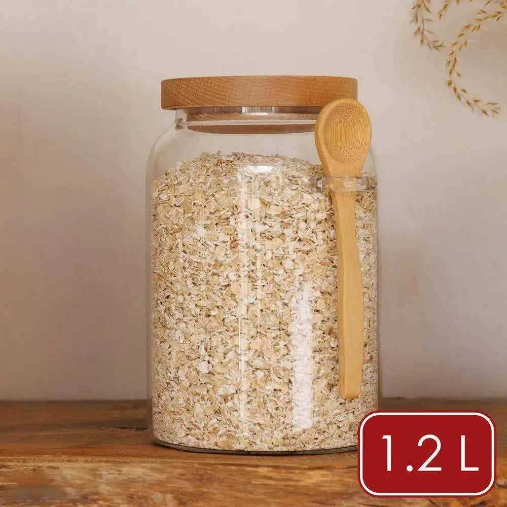 Glass jar with wooden lid and spoon filled with oats, labeled 1.2L, on a wooden surface.