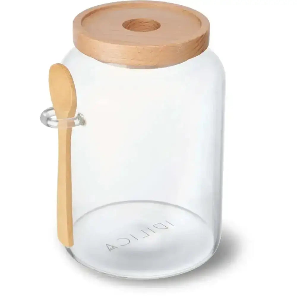 Clear glass jar with wooden lid and spoon on a white background