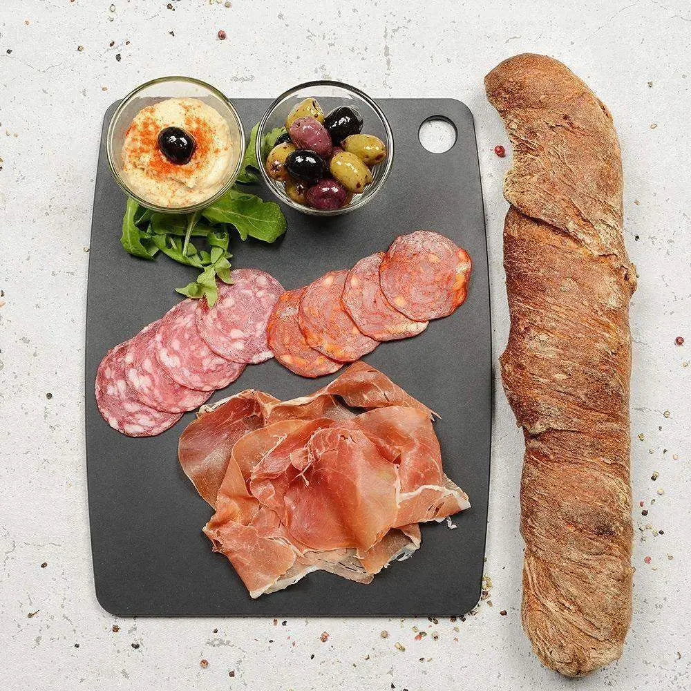 Platter of cured meats, olives, and bread on a gray slate surface.