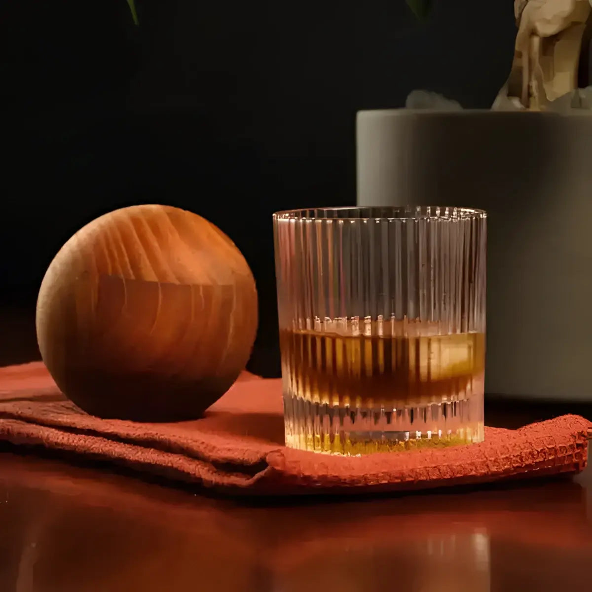 Jan Hendrik Allure ribbed tumbler glass with whiskey and ice on rust cloth, premium kitchenware from Cookin Stores