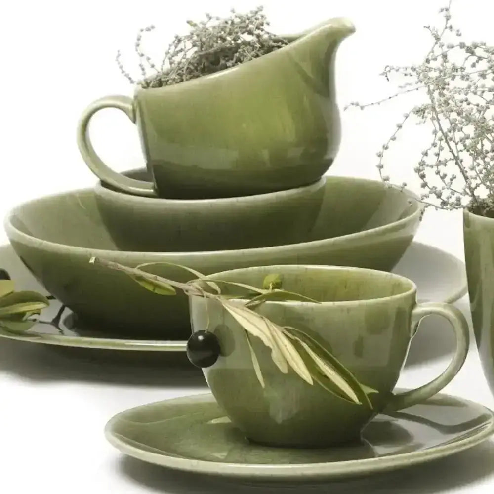 Green ceramic tableware set including cups, bowls, and a gravy boat on a white background.