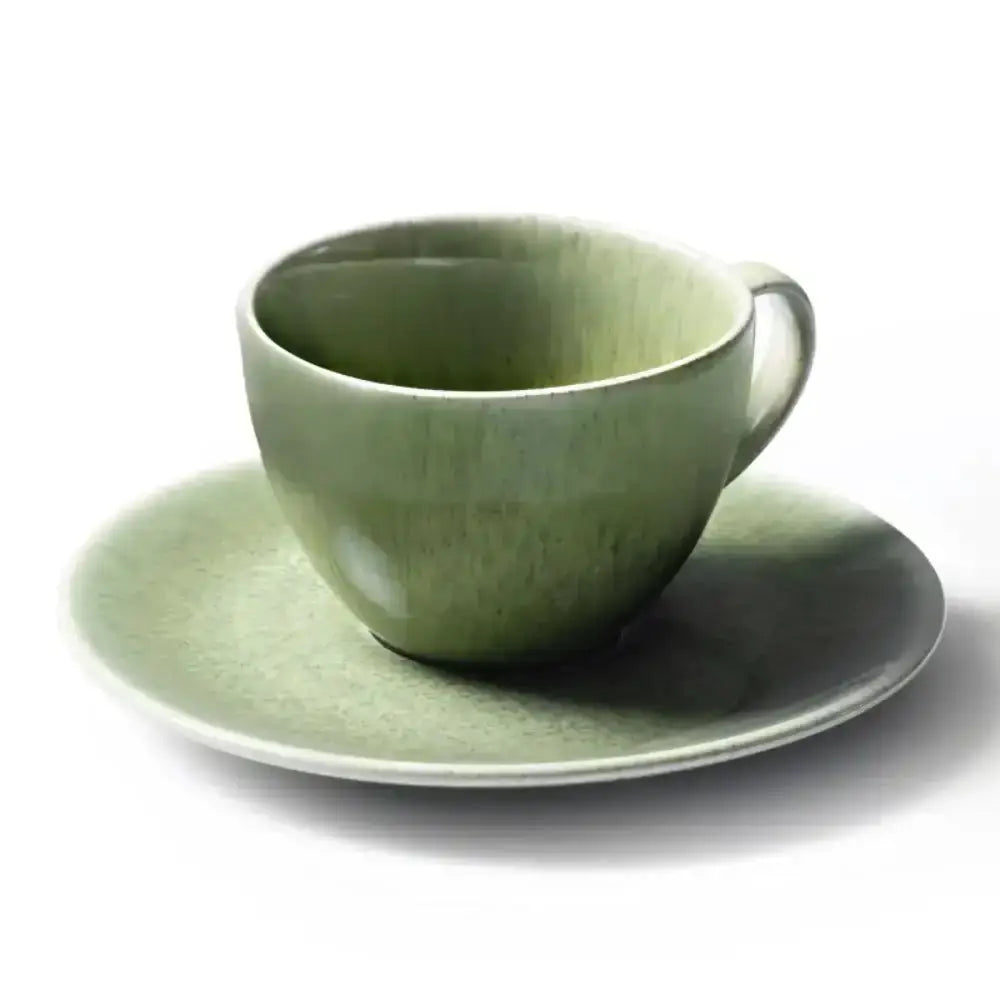 Green ceramic cup and saucer on a white background